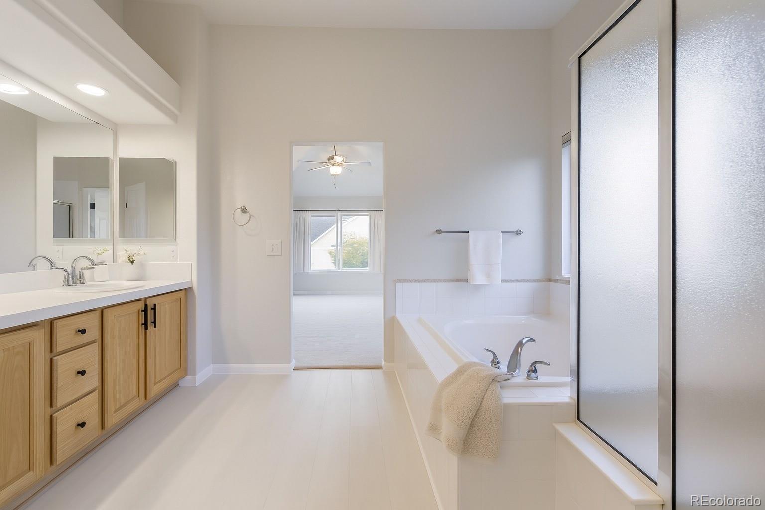 13867 Fillmore Street Thornton, CO 80602 - Photo 13 of 24 a en suite bathroom with a granite countertop sink tub and mirror