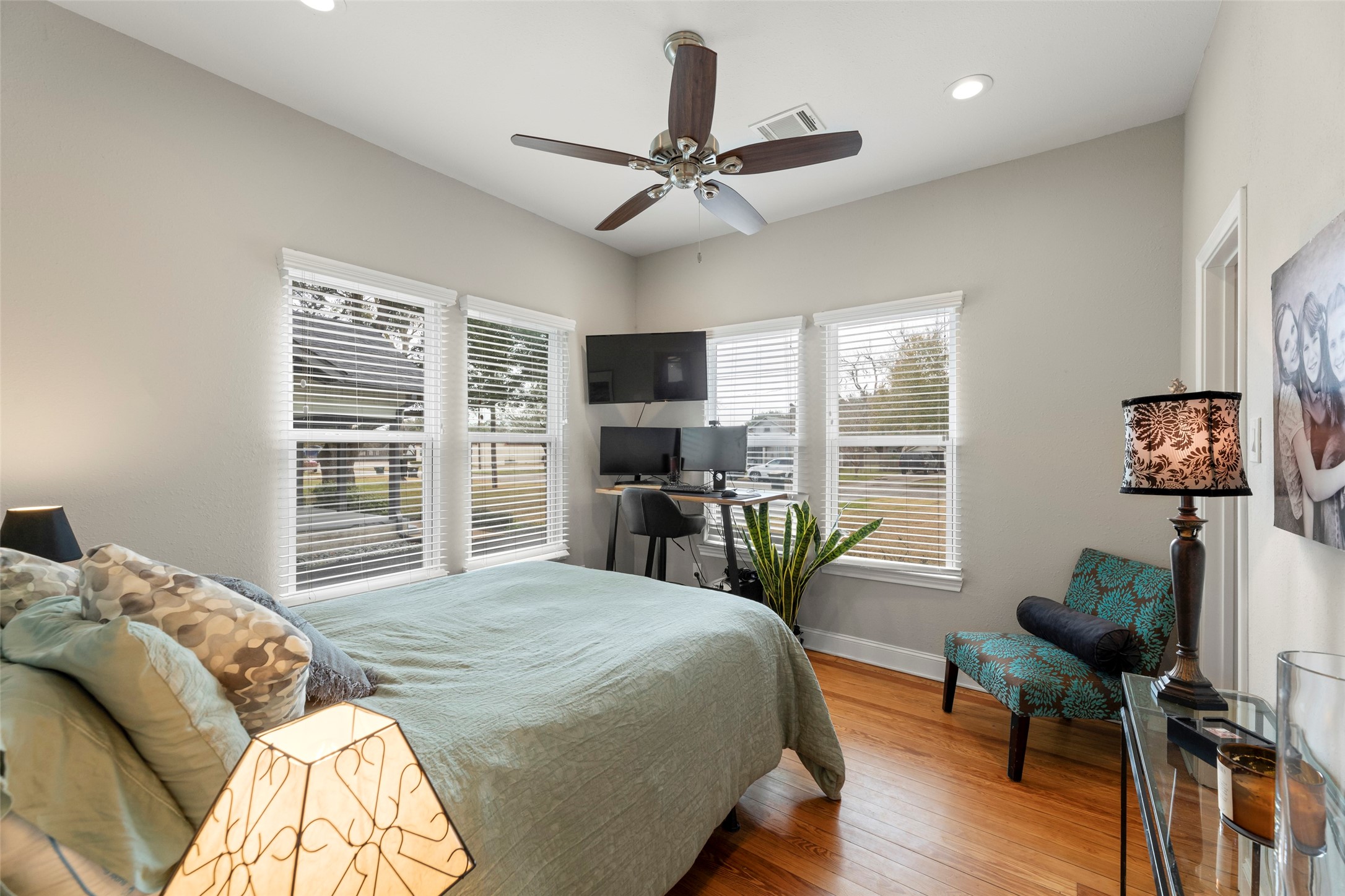 711 4th Street Sealy, TX 77474 - Photo 24 of 37 Cozy bedroom with ample natural light from multiple windows, featuring a ceiling fan and wood flooring.