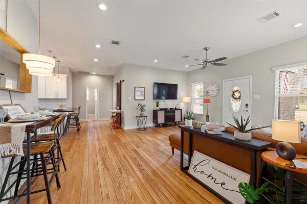 a living room with furniture a wooden floor and a view of kitchen