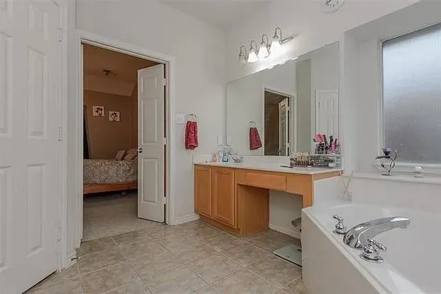 a bathroom with a tub a sink and mirror