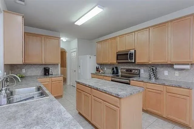 a kitchen with granite countertop a sink a stove top oven a counter space and cabinets