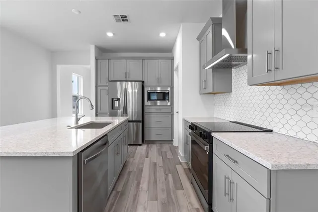 a kitchen with granite countertop kitchen island wooden cabinets a refrigerator stove and sink