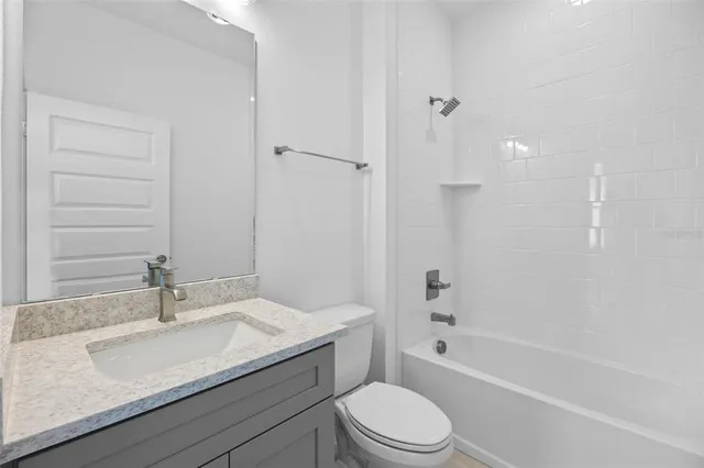 a bathroom with a granite countertop sink a toilet and shower