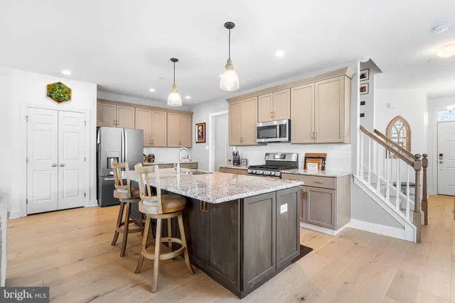 a kitchen with stainless steel appliances kitchen island granite countertop a table chairs and a refrigerator