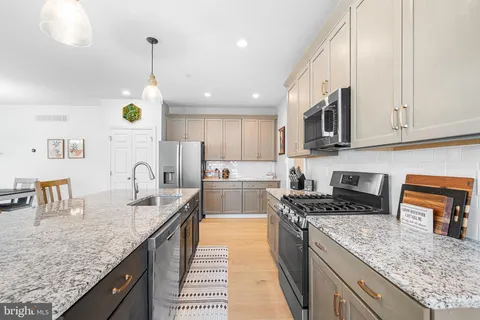 a kitchen with stainless steel appliances granite countertop a sink a stove and a wooden cabinets