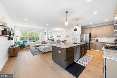 a large kitchen with kitchen island a large counter top space a sink a window and stainless steel appliances