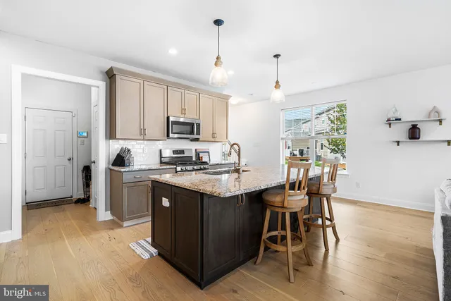 a kitchen with stainless steel appliances granite countertop a stove top oven a refrigerator a sink and a dining table with wooden floor