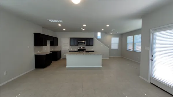 a large living room with stainless steel appliances kitchen island a large counter top a stove a microwave and a refrigerator