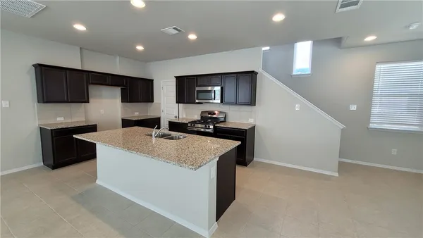 a kitchen with kitchen island stainless steel appliances a sink and a refrigerator