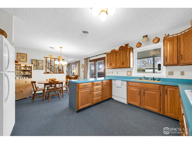 a kitchen with stainless steel appliances granite countertop a refrigerator a sink dishwasher a dining table and chairs with wooden floor