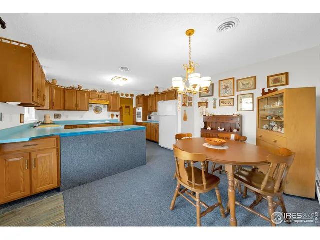 a dining room with stainless steel appliances kitchen island granite countertop a table chairs and a refrigerator