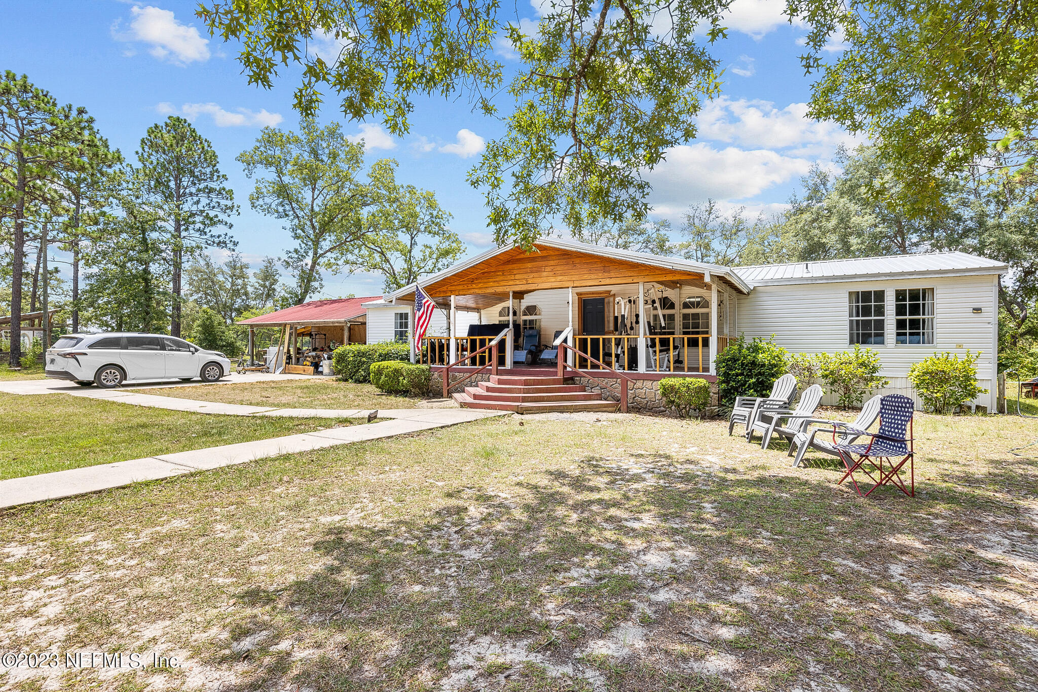 7730 Ranchette Road Keystone Heights, FL 32656 - Photo 2 of 30 a view of a swimming pool with lawn chairs under an umbrella