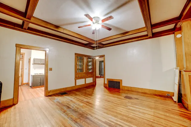 a view of an empty room with wooden floor and a ceiling fan