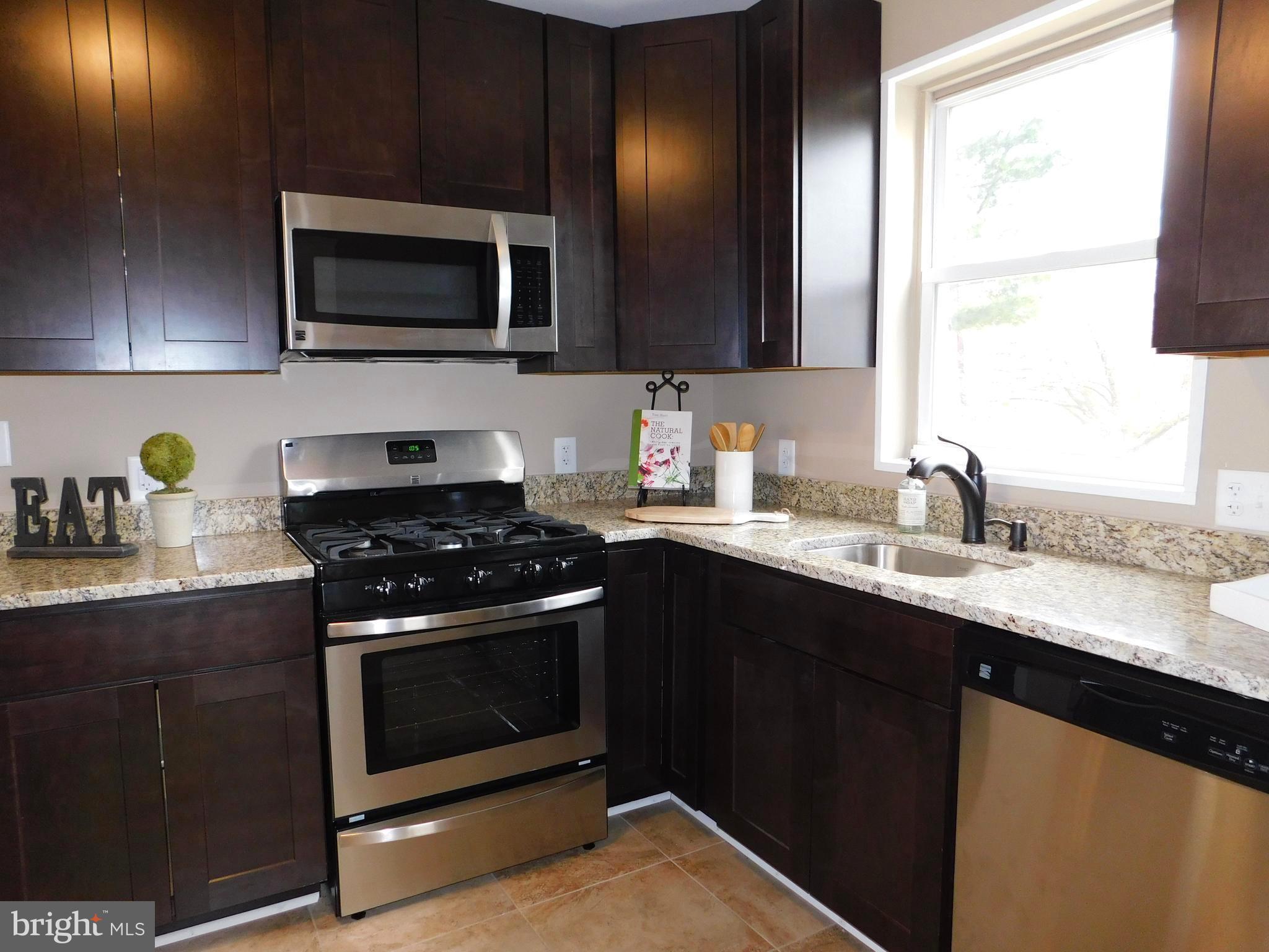 606 Andover Road Linthicum, MD 21090 - Photo 12 of 29 a kitchen with stainless steel appliances a sink a stove a microwave and wooden cabinets