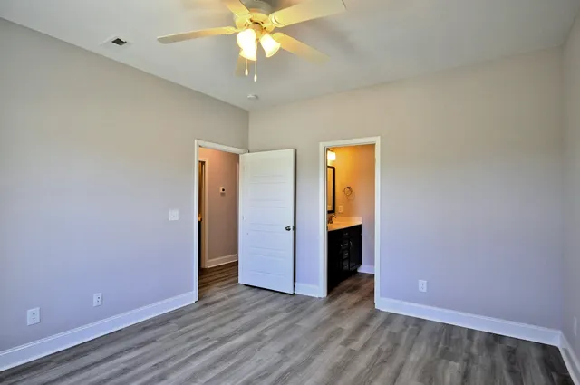 an empty room with wooden floor and a ceiling fan