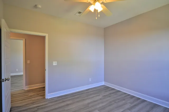 an empty room with wooden floor and chandelier fan