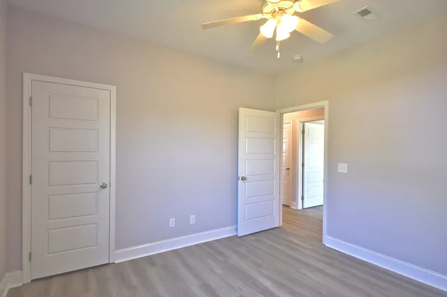 an empty room with wooden floor fan and window
