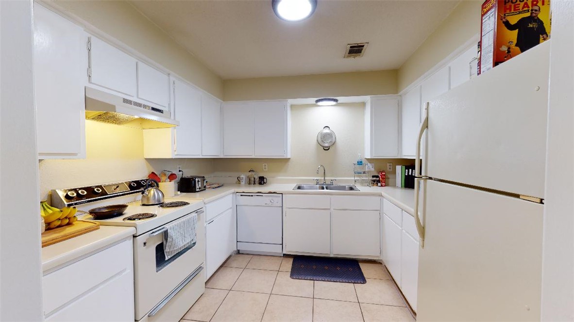 1809 Treehouse Trail, Unit D College Station, TX 77845 - Photo 6 of 23 a kitchen with a sink a refrigerator and cabinets