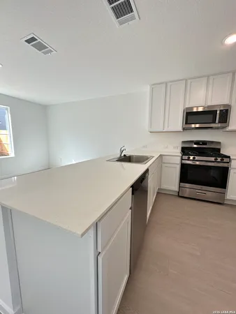 a kitchen with stainless steel appliances a stove a sink a microwave and cabinets