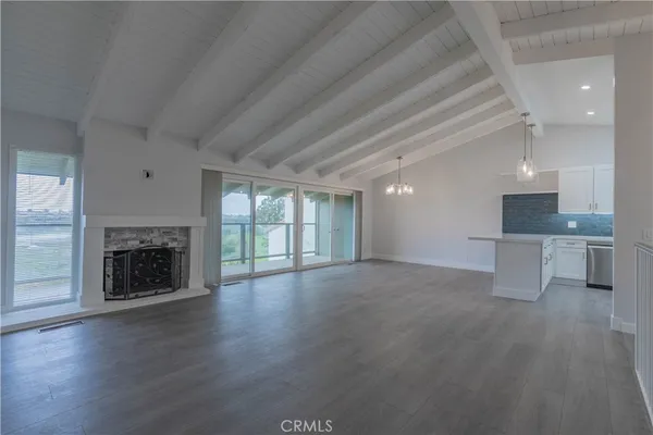an empty room with wooden floor fireplace and windows