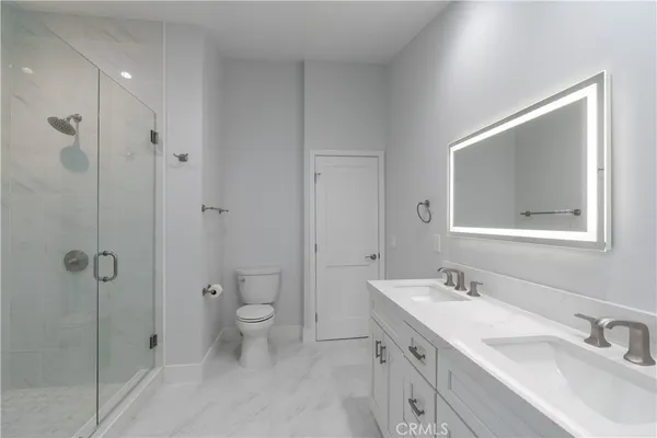 a bathroom with a double vanity sink toilet and shower