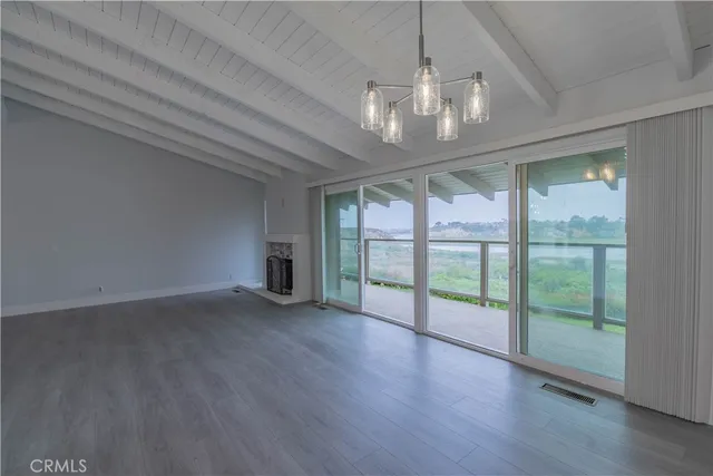 a view of an empty room with wooden floor and a floor to ceiling window