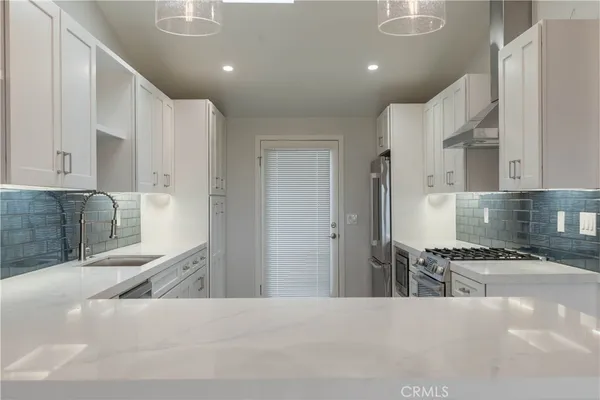 a kitchen with stainless steel appliances kitchen island granite countertop a refrigerator and a sink