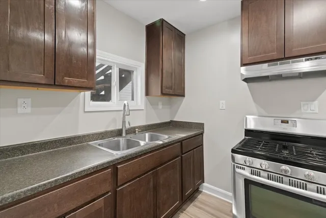 a kitchen with granite countertop stainless steel appliances a sink stove and cabinets