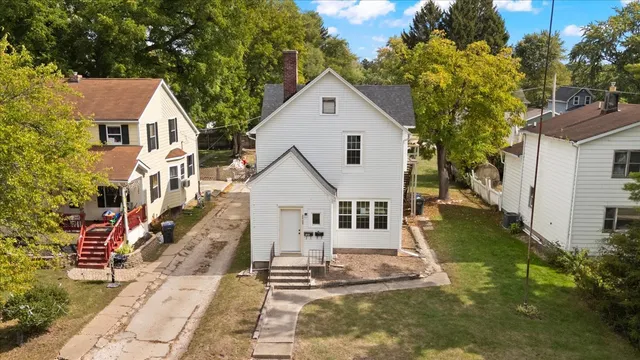a view of white house with a yard and potted plants