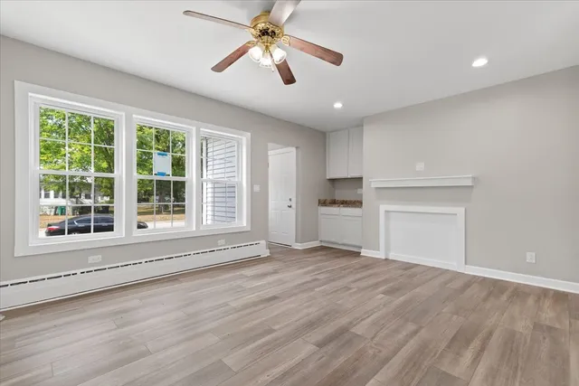 a view of empty room with wooden floor and fan