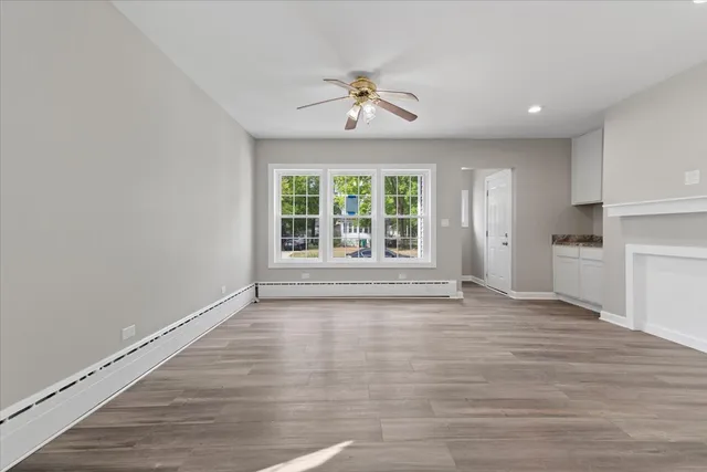 a view of an empty room with a window and wooden floor