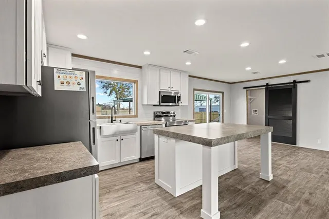 a open kitchen with stainless steel appliances granite countertop a stove top oven a sink dishwasher and a refrigerator with wooden floor