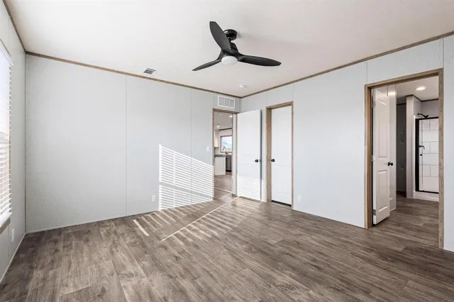 a view of empty room with wooden floor and ceiling fan