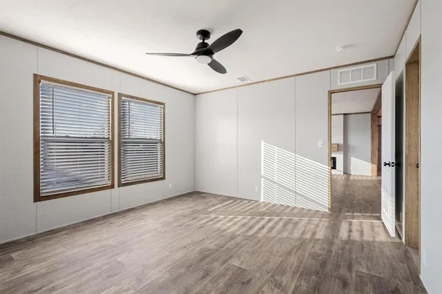 a view of empty room with wooden floor and fan