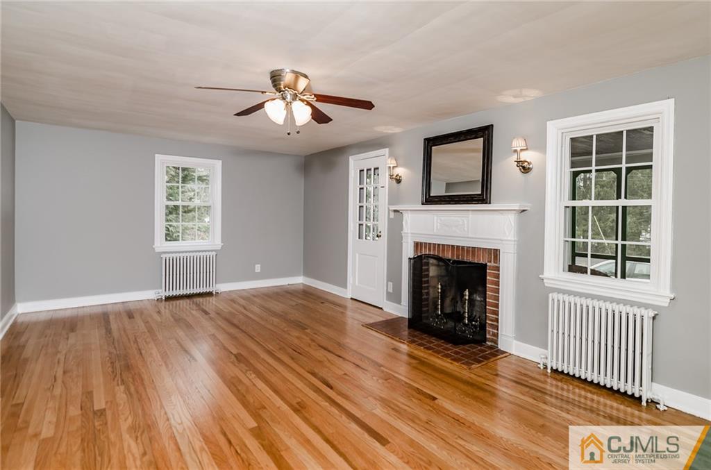 127 Plainsboro Road Cranbury, NJ 08512 - Photo 4 of 25 a view of an empty room with wooden floor fireplace and a window