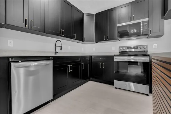 a kitchen with stainless steel appliances granite countertop a stove a sink and a microwave