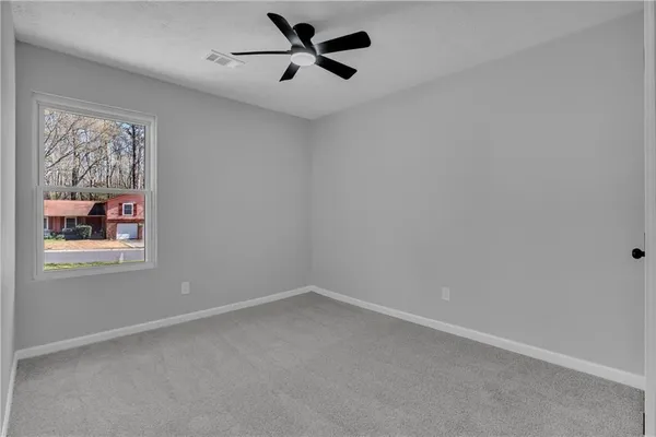 an empty room with a window and a fan