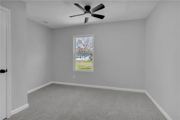 an empty room with a window and a fan