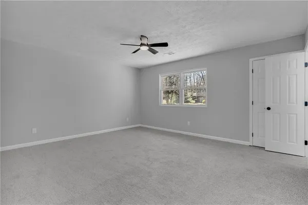 an empty room with windows and fan