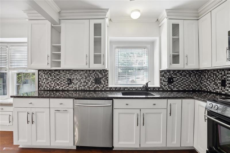 a kitchen with granite countertop white cabinets and sink