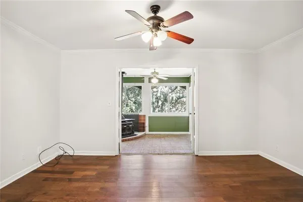 an empty room with wooden floor fan and windows