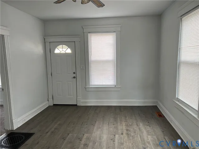 an empty room with wooden floor and windows