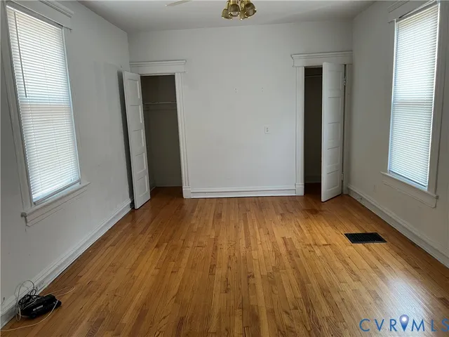 an empty room with wooden floor and windows