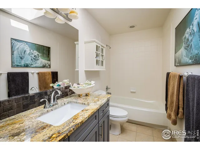 a bathroom with a granite countertop sink toilet and painting on the wall