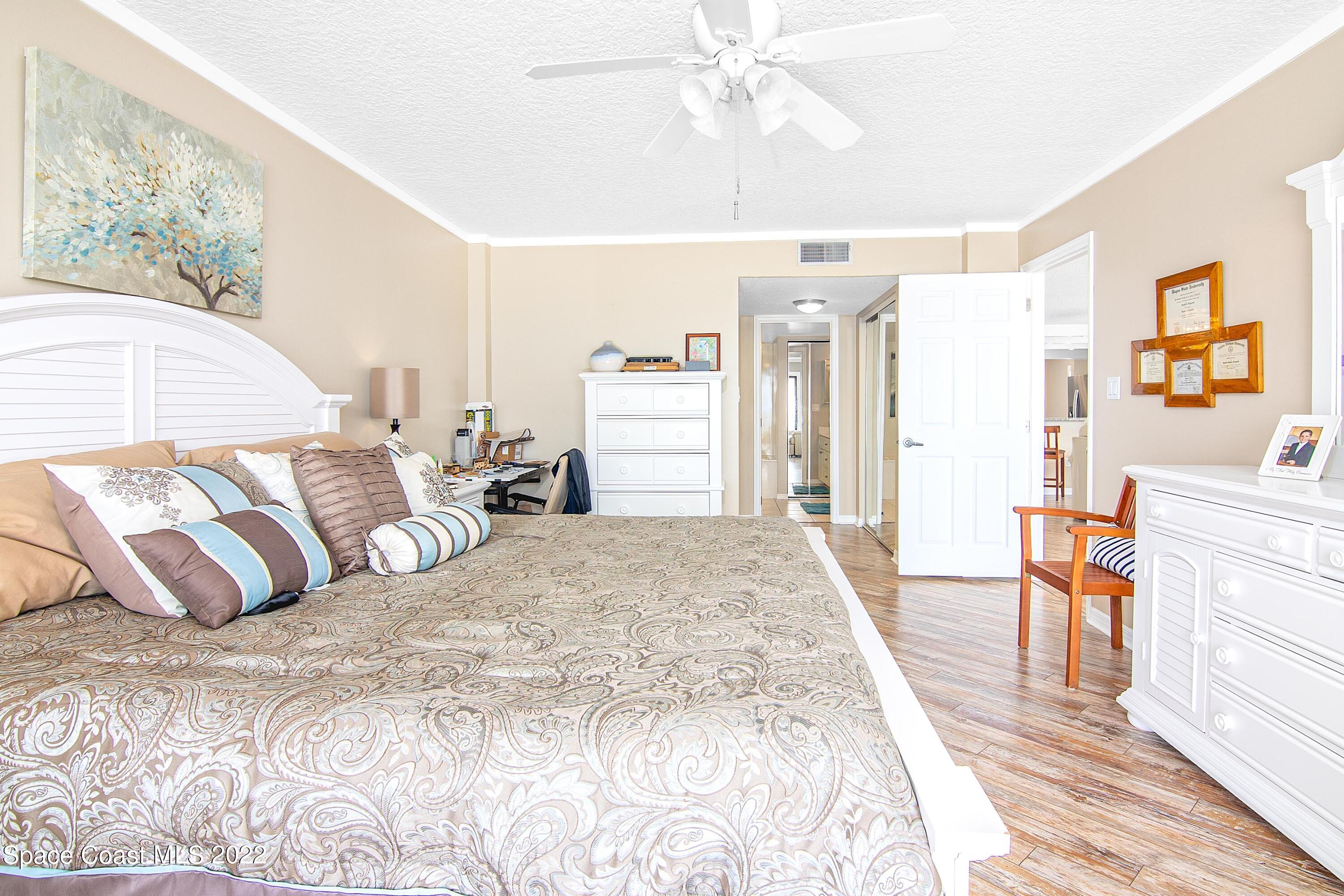 6770 Ridgewood Avenue, Unit 1001 Cocoa Beach, FL 32931 - Photo 24 of 57 a bedroom with a large bed and a chandelier