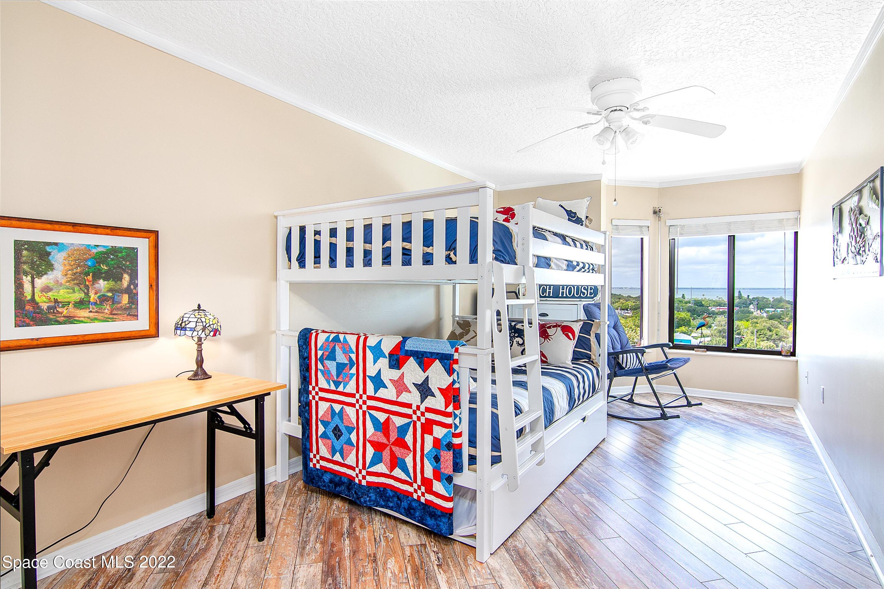 6770 Ridgewood Avenue, Unit 1001 Cocoa Beach, FL 32931 - Photo 33 of 57 a bedroom with furniture a baby crib a chandelier and a wooden floor