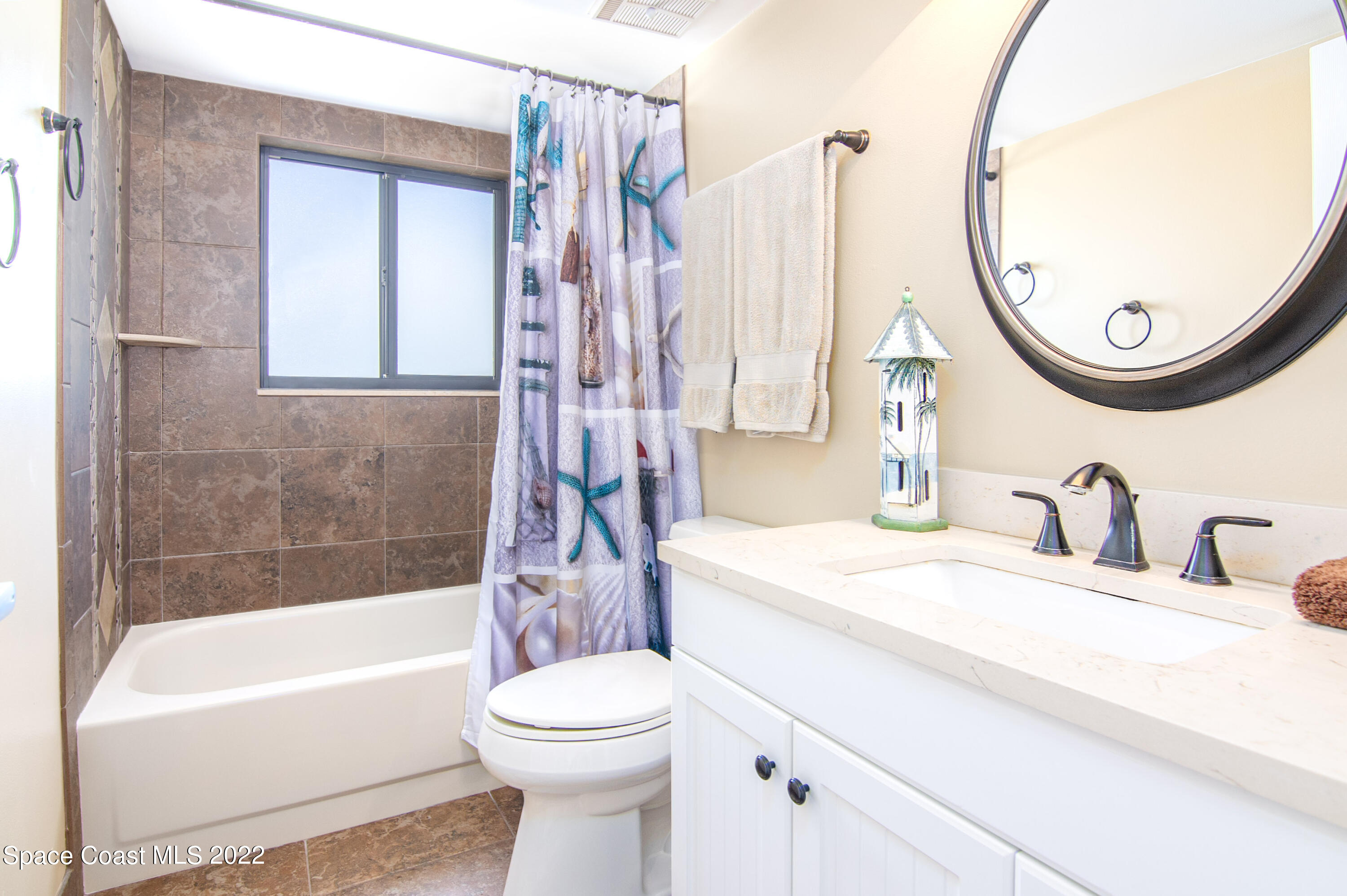 6770 Ridgewood Avenue, Unit 1001 Cocoa Beach, FL 32931 - Photo 36 of 57 a bathroom with a sink a toilet and a mirror
