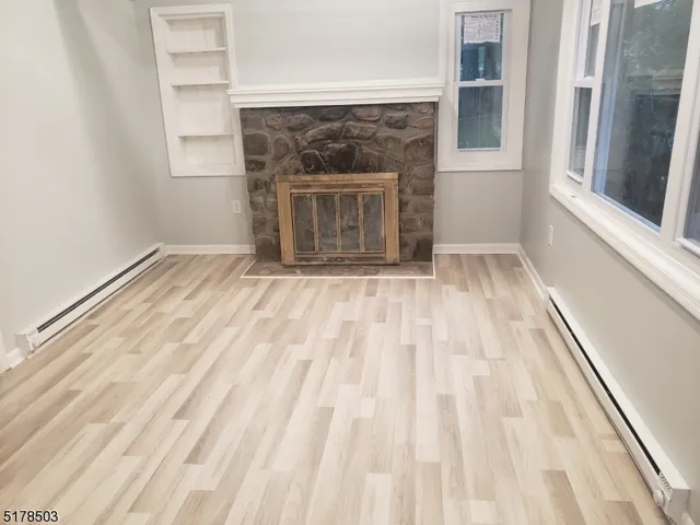 a view of empty room with wooden floor and fireplace