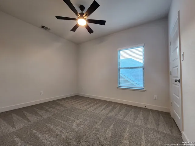 an empty room with a window and a fan