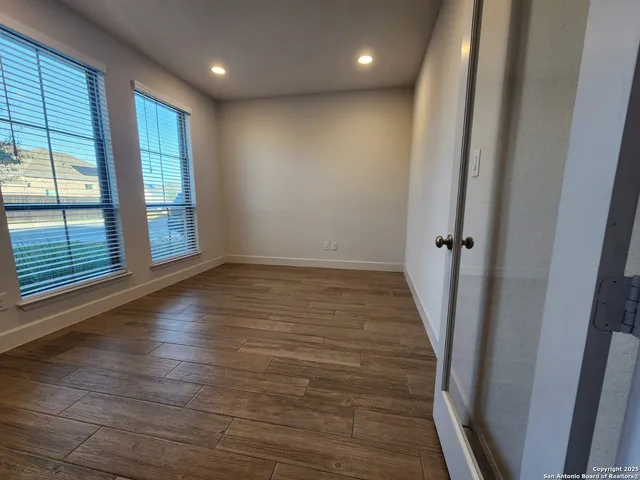 an empty room with wooden floor and windows